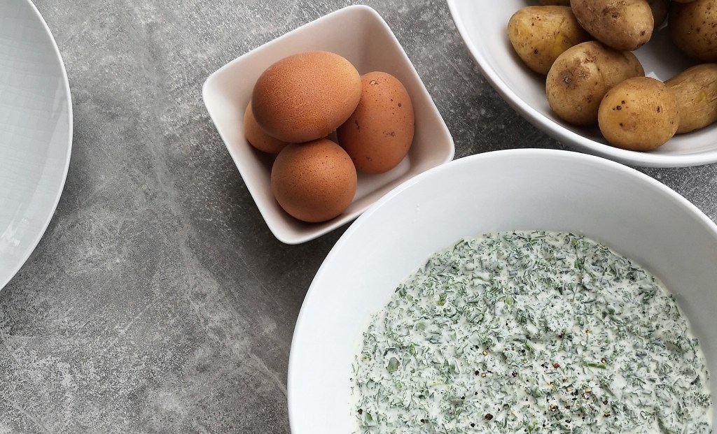 In drei weißen Schalen auf einem Tisch befinden sich Eier, Kartoffeln und Frankfurter Grüne Soße