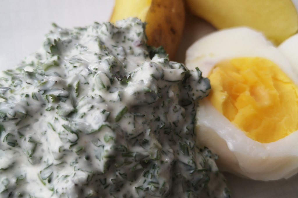 Ein Klecks leckere Grüne Soße mit einem halbierten Ei und Pellkartoffeln.